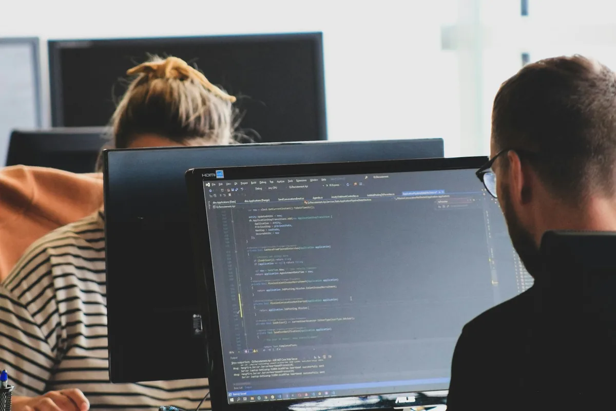 Engineers working through code on monitors in a bright office